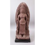 A 12TH CENTURY STYLE CAMBODIAN KHMER STYLE RED SANDSTONE CARVING OF A FOUR ARMED DEITY. 52cms high.
