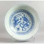 A LARGE MING STYLE BLUE AND WHITE CIRCULAR DISH decorated with dragons. 15ins diameter.