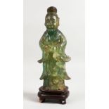 A CHINESE GREEN QUARTZ FIGURE on a wooden stand. 8ins high.
