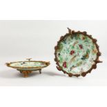 A PAIR OF CELADON DISHES enamelled with birds and flowers in a gilt mount.