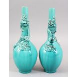 A PAIR OF ORIENTAL TURQUOISE GROUND PORCELAIN DRAGON BOTTLE VASES, both vase with moulded dragons