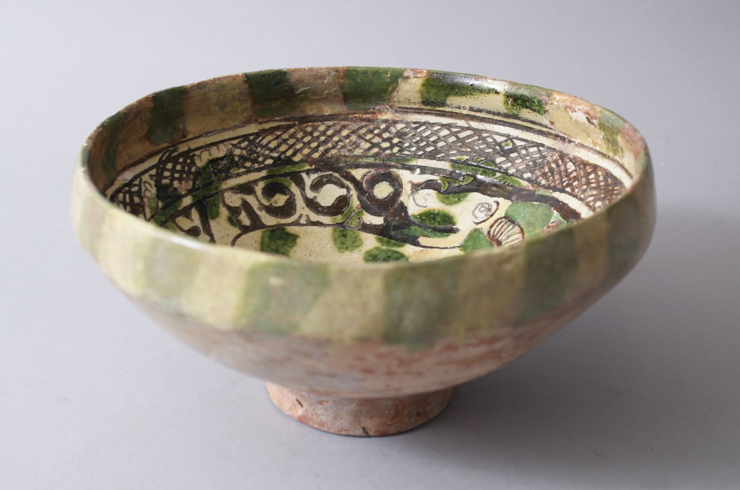 A 12TH-13TH CENTURY GARUS GLAZED POTTERY BOWL bearing a rams image amongst foliage.