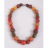 A JAPANESE CARVED & STAINED TAGUA NUT OJIME BEAD NECKLACE, consisting of 27 beads, 48.5cm long,