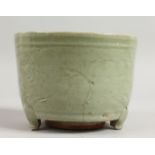 AN EARLY CHINESE CIRCULAR CELADON CENSER on three legs. 5.5ins diameter.