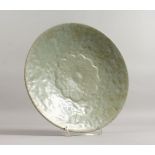 A CELADON CIRCULAR DISH with a flower in relief. 11ins diameter.