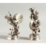 A PAIR OF AMUSING SILVER FIGURES playing musical instruments. 4.5ins high.