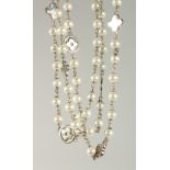 A long decorative pearl necklace, interspersed with flower head design. 145cm long.