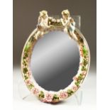A MEISSEN STYLE OVAL MIRROR, with cherub and floral decoration. 30cms high.