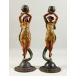 A PAIR OF CAST METAL, PAINTED CANDLESTICKS, modelled as a male and female figure, supported on