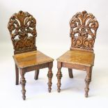 A PAIR OF VICTORIAN OAK HALL CHAIRS, with carved backs, solid seats, on turned and carved legs.