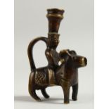 AN EASTERN SMALL BRONZE CANDLESTICK, modelled as a man riding a ram. 12cms high.