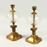 A PAIR OF 20TH CENTURY BRASS AND GLASS TABLE LAMPS, with bulbous glass reservoirs. 37cms high.