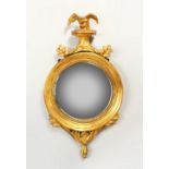 A SMALL REGENCY GILTWOOD CONVEX WALL MIRROR, with eagle cresting and leaf carved frame. 71cms x