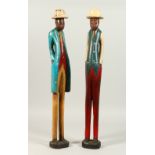 A PAIR OF TALL, THIN, CARVED AND PAINTED WOOD MALE FIGURES, 20TH CENTURY, standing with hands in