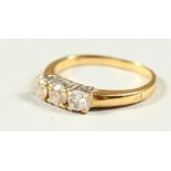 AN 18CT GOLD THREE STONE DIAMOND RING.