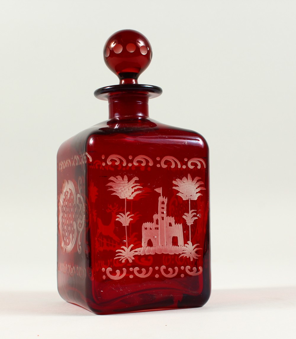 A BOHEMIAN SQUARE SHAPE RUBY GLASS DECANTER, engraved with a castle and a deer. 19cms high.