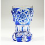 A BOHEMIAN BLUE TINTED BEAKER-VASE with cut base. 5ins high.