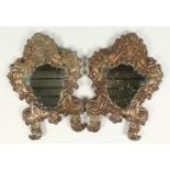 A PAIR OF ITALIAN METAL SHAPED MIRRORS, with crest and scrolled decoration. 12ins high.