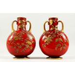 A PAIR OF LATE 19TH CENTURY RED OPAQUE GLASS TWIN-HANDLED MOON FLASKS, with gilded decoration, on
