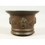 A 17TH CENTURY CAST BRONZE MORTAR, with mask and shell decoration. 13.5cms diameter.
