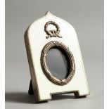 A SMALL RUSSIAN SILVER AND GUILLOCHE ENAMEL PHOTOGRAPH FRAME, arch shaped with ribbon and bow mount.