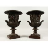 A PAIR OF CLASSICAL STYLE CAMPAGNA SHAPE URNS, decorated with figures, on square bases. 32cms high.