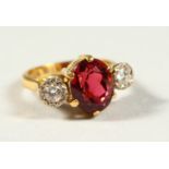 AN 18CT GOLD THREE STONE DIAMOND AND RED STONE RING.