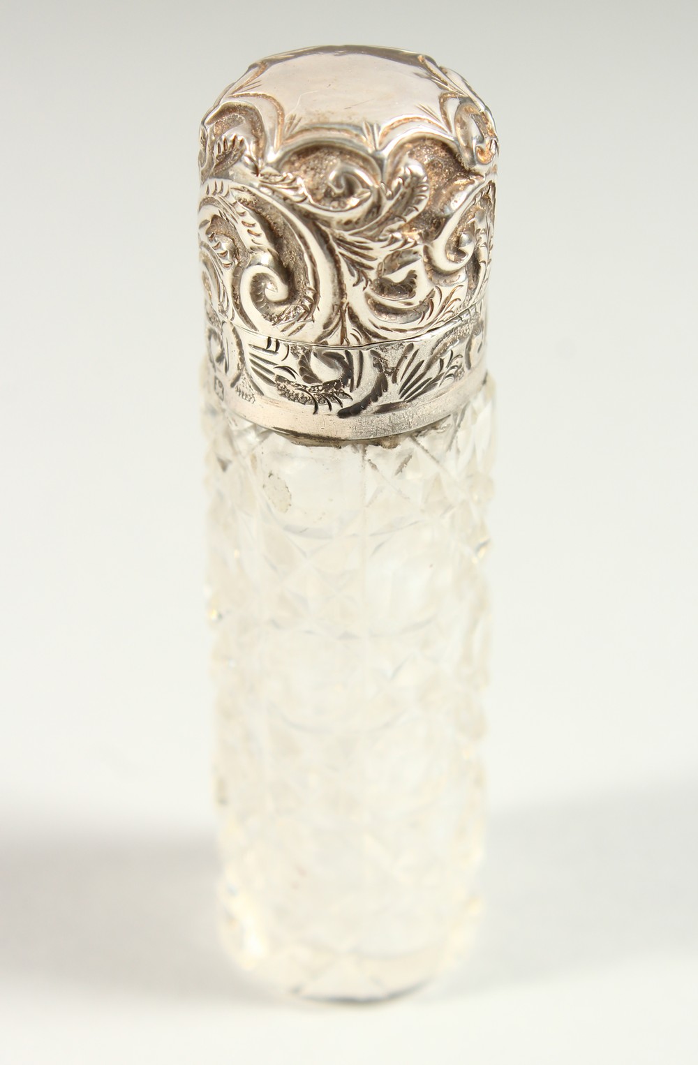 A VICTORIAN PLAIN CUT GLASS SCENT BOTTLE with repousse silver top and plain glass stopper.
