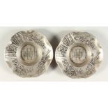 A PAIR OF CAST METAL DISHES, the centre with calligraphy decoration. 11cms diameter.