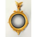 A REGENCY GILTWOOD CONVEX WALL MIRROR, with eagle cresting, ball applied frame, and leaf carved