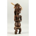A CARVED WOOD TRIBAL FIGURE, of a standing male, hands clasped together. 44cms high.