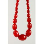 A RED AMBER BEAD NECKLACE. Largest Bead: 30mm. Overall Length: 78cms.