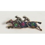 A 9CT GOLD AND SILVER JOCKEY BROOCH, set with sapphires, rubies and emeralds.