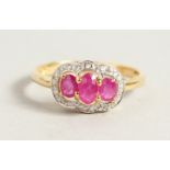 A 9CT GOLD OVAL THREE-STONE RUBY AND DIAMOND RING.