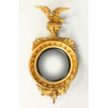 A REGENCY GILTWOOD CONVEX WALL MIRROR, with eagle cresting, ball applied frame, and leaf carved