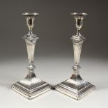 A PAIR OF EDWARD VII SILVER CANDLESTICK, on square loaded bases. London 1906. Maker: The Hutton's.