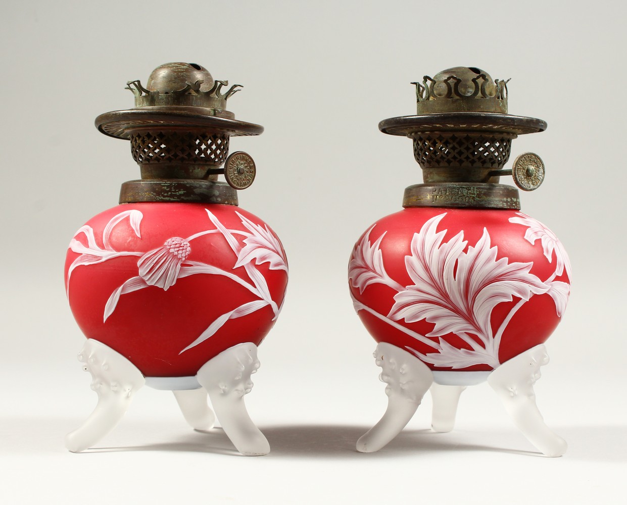 A PAIR OF RED AND WHITE CAMEO GLASS OIL LAMP BASES, with flowers, leaves and thistles. 7.5ins high.