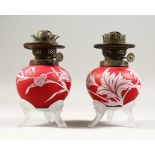 A PAIR OF RED AND WHITE CAMEO GLASS OIL LAMP BASES, with flowers, leaves and thistles. 7.5ins high.