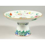 A PORCELAIN PEDESTAL DISH, decorated with flowers. 18.5cms diameter.