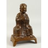 A BRONZE FIGURE OF A SEATED SCHOLAR, hands clasped together. 23cms high.