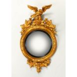A REGENCY GILTWOOD CONVEX WALL MIRROR, with eagle cresting and leaf carved frame. 102cms high x