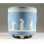 A WEDGWOOD PALE BLUE JASPERWARE CIRCULAR JARDINIERE, with classical scene on three bun feet. 8ins