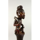 A TRIBAL CARVED WOOD FIGURAL PESTLE. 40cms high.