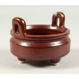 A SMALL FLAMBE STYLE TWIN-HANDLED POTTERY CENSER, on three feet. 12cms diameter.
