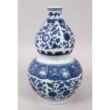 A CHINESE MING STYLE BLUE AND WHITE PORCELAIN DOUBLE GOURD VASE, decorated with formal scrolling