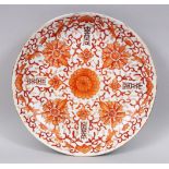 A 20TH CENTURY CHINESE IRON RED PORCELAIN PLATE, decorated with formal scroll and foliage and