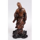 A JAPANESE MEIJI PERIOD CARVED HARDWOOD FIGURE OF A SCHOLAR, stood with his head tilted, holding a