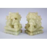 A PAIR OF 20TH CENTURY CHINESE JADE / JADELIKE HARDSTONE LION DOGS, both sat upon carved pedestal