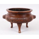 A 19TH / 20TH CENTURY CHINESE BRONZE TRIPOD CENSER, eith moulded lion dog head handles, panels of