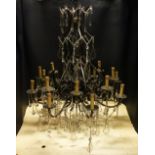 A GOOD LARGE PATINATED BRASS AND CUT GLASS CHANDELIER, comprising two tiers of eight curving